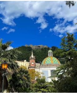 a building with a clock tower in front of a mountain at Salerno Eremita Apartment in Salerno