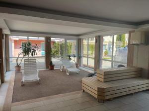 - une terrasse couverte avec 2 chaises, un banc et des fenêtres dans l'établissement Bella Wellness Apartman, à Hajdúszoboszló