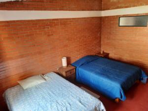 a bedroom with two beds and a brick wall at La Cabaña de Tano in Mineral del Monte