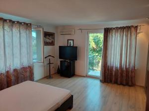 sypialnia z łóżkiem, telewizorem i oknem w obiekcie Casa Doros w mieście Eforie Sud