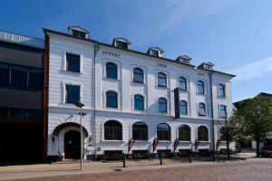 ein weißes Gebäude mit roten Stühlen davor in der Unterkunft Hotel Phønix Brønderslev in Brønderslev