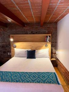 een slaapkamer met een groot bed met een bakstenen muur bij 108, LOFT CONFORTABLE, BALCON 1 CALLE BELLAS ARTES in Mexico-Stad