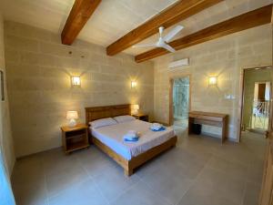 a bedroom with a bed and two tables and a fan at Ta' Ganna Farmhouse in Sannat