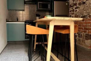 een houten tafel in een keuken met twee krukken bij 109 SUITES DONCELES C/BALCON CENTRO HISTÓRICO CDMX in Mexico-Stad