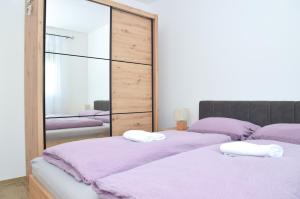 a bedroom with two beds with purple sheets and a mirror at Apartman RIO in Jajce