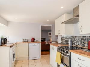 a kitchen with white cabinets and a stove top oven at Livet Cottage in Tomintoul