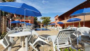 a patio with white chairs and blue umbrellas at Pousada Estalagem Da Serra in Serra do Cipo