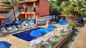 a swimming pool with umbrellas and chairs and a resort at Pousada Estalagem Da Serra in Serra do Cipo