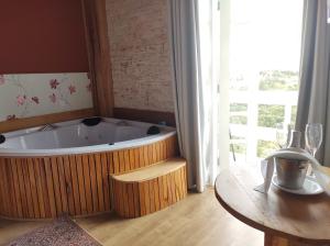 uma grande banheira num quarto com uma mesa em Pousada Miraggio em Campos do Jordão
