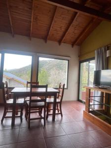 comedor con mesa, sillas y ventanas en Casas Pura Vida en Villa General Belgrano