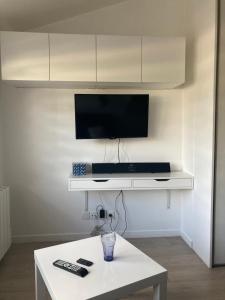 salon ze stołem i telewizorem na ścianie w obiekcie Studio tout équipé au calme w mieście Cappelle-la-Grande