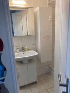 a white bathroom with a sink and a mirror at Studio tout équipé au calme in Cappelle-la-Grande