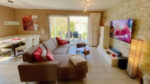 a living room with a couch and a tv and a table at Ferienhaus Foresta in Göhren-Lebbin