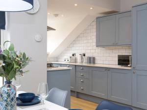 a kitchen with blue cabinets and a table with chairs at Anchors Rest in Y Felinheli