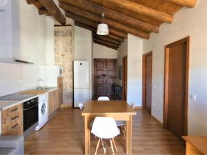 cocina con mesa de madera y sillas blancas en Casa Tropiet, en Beceite