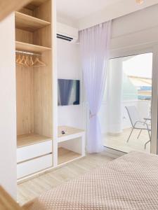 a bedroom with a bed and a tv and a window at Ifigenia Sea View Apartments in Chrysi Ammoudia