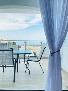 a table and chairs on a balcony with a view of the beach at Ifigenia Sea View Apartments in Chrysi Ammoudia