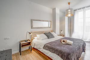 a white bedroom with a large bed and a table at 3.1 Apartamento Cap del Bosc in Puigcerdà