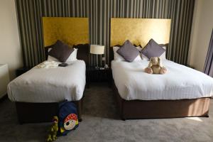 a hotel room with two beds with a teddy bear on them at Talbot Hotel Carlow in Carlow