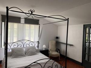 Molières-sur-CèzeにあるMaison des Ingénieursのベッドルーム(黒い天蓋付きベッド1台、椅子付)