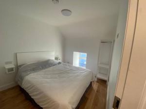 a white bedroom with a bed and a window at Devane House in Portmagee