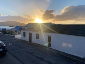 a white building with the sun setting behind it at Devane House in Portmagee