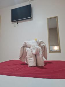 a stuffed elephant sitting on a bed with a television at Pousada Perola Dourada Maceió in Maceió