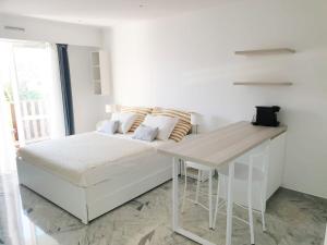 a white bedroom with a bed and a desk at Beautiful T1 with sea view in Nice
