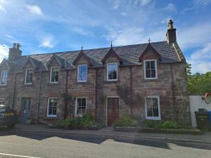 an old brick house with a roof on a street at Clematis Cottage, Fortrose in Fortrose