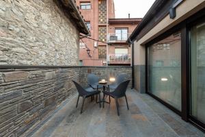 een patio met stoelen en een tafel aan een bakstenen muur bij CERDANYA MOUNTAIN RESIDENCES in Bellver de Cerdanya 
