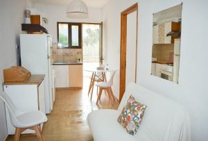 a living room with a white couch and a kitchen at Ελαία Apartments in Edipsos