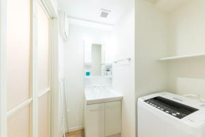 uma casa de banho branca com um lavatório e uma máquina de lavar roupa em SG RESIDENCE INN HAKATAEKIMINAMI - Vacation STAY 61959v em Fukuoka