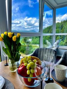 una mesa con un bol de frutas y copas de vino en Apartament 26 Resort Kozubnik blisko Szczyrk - 5D Apartamenty, en Porąbka