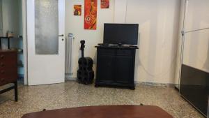 a room with a television and a guitar next to a door at Appartamento luminoso, semplice con ogni comfort in Lido di Ostia