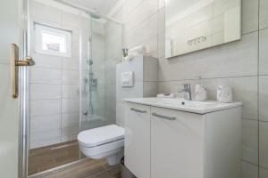 a white bathroom with a toilet and a sink at Apartments Punta in Kruševo +79 photos