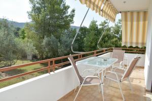 a balcony with a glass table and chairs at Ελαία Apartments in Edipsos