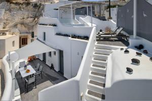 a staircase leading up to a white building with a table at Astrea Suites Feggaropetra Cave House in Fira