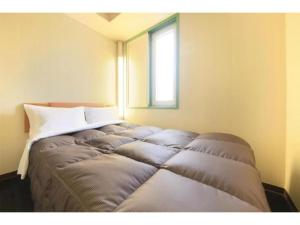 a bed in the corner of a room with a window at R&B Hotel Sendai Hirosedori Ekimae - Vacation STAY 39668v in Sendai