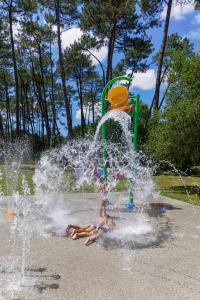 a child playing in a fountain in a park at Tente Indiana Chênes - La Téouleyre in Saint-Julien-en-Born