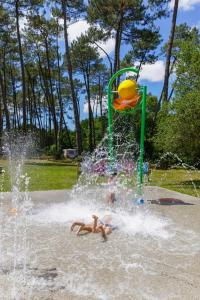 dwoje ludzi bawiących się w fontannie w parku w obiekcie Tente Indiana Chênes - La Téouleyre w mieście Saint-Julien-en-Born