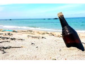 a bottle of beer sitting in the sand on the beach at Pensione Shimado - Vacation STAY 37555v in Shimonoseki