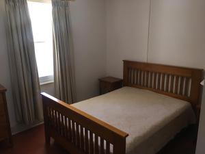 a bedroom with a wooden bed and a window at Old Homestead - The Dutchmans Stern Conservation Park in Quorn