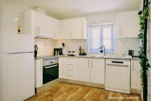 a kitchen with white cabinets and white appliances at Almoura Ladeira in Évora