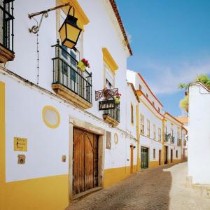 een straat in een oude stad met gele en witte gebouwen bij Almoura Ladeira in Évora