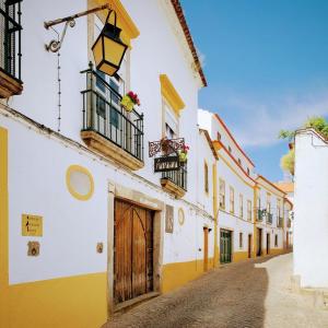 a street in an old town with yellow and white buildings at Almoura Ladeira in Évora