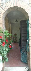 un ingresso a un patio con fiori rossi e una pianta di La Campagna di Rosy a Genzano di Roma
