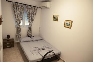 małe łóżko w pokoju z oknem w obiekcie Three Palms Apartments Novakovic w Petrovacu na Moru