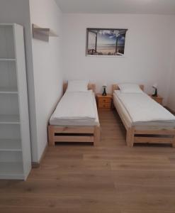 two beds in a room with wooden floors at Arka Mielenko in Mielenko