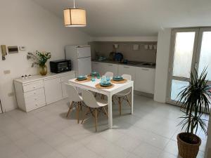 a kitchen with a white table with chairs and a refrigerator at La Casa BluMare in Porto Recanati