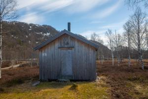 a small wooden shed with a door in a field at Unique cabin Sikringsbua in Sirdal in Tjørhom